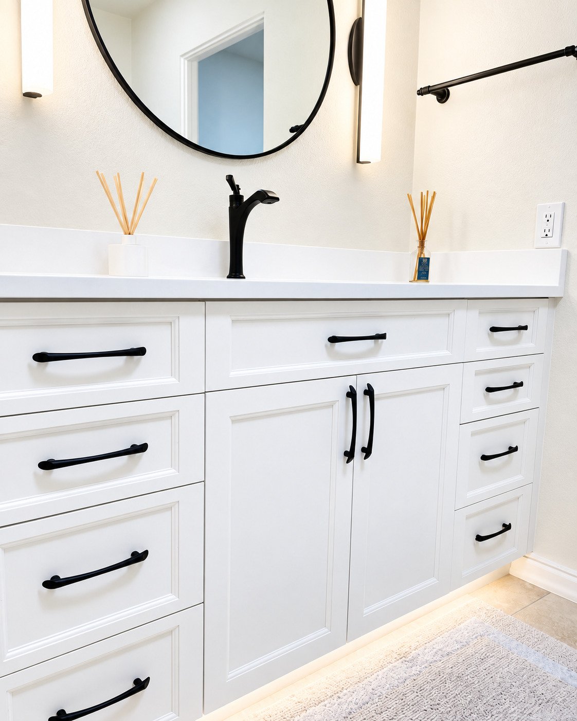 Angled close view of white vanity cabinetry and black hardware