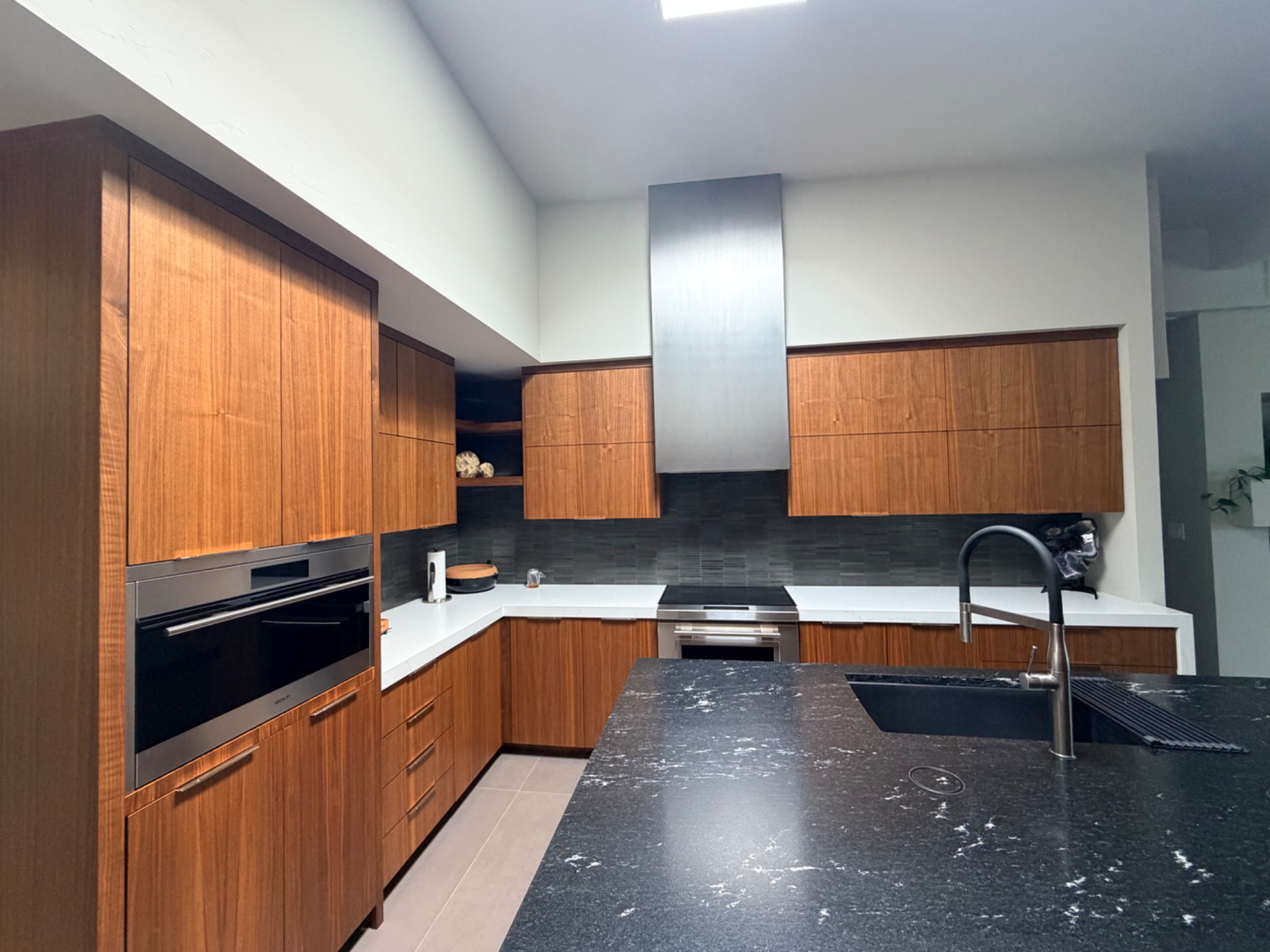 Walnut kitchen cabinetry surrounding a dark stone island