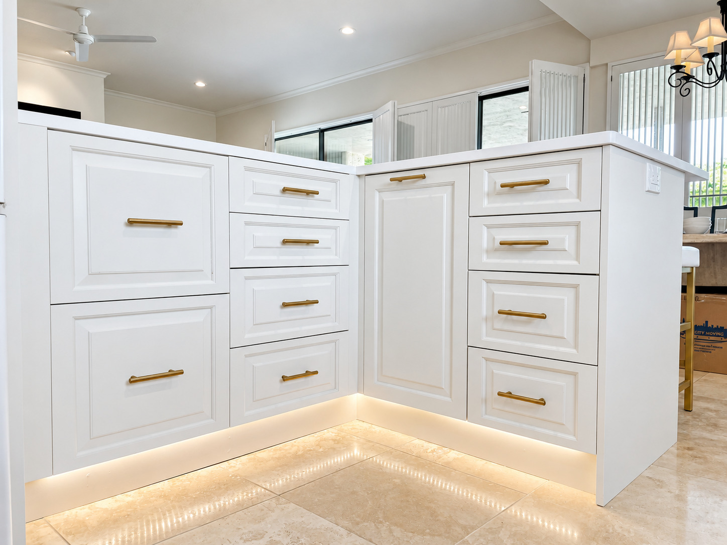 Close view of white kitchen island cabinetry with brass hardware